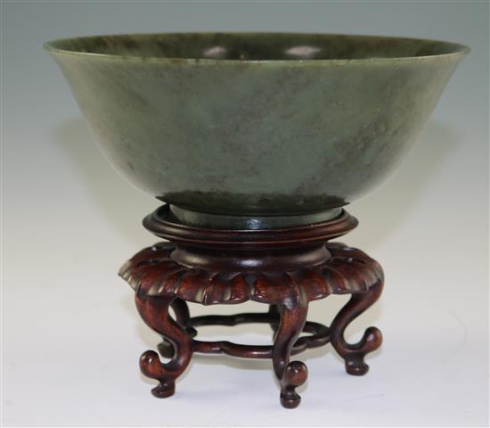 A Chinese spinach green jade bowl, 18th century, diameter 19cm, wood stand